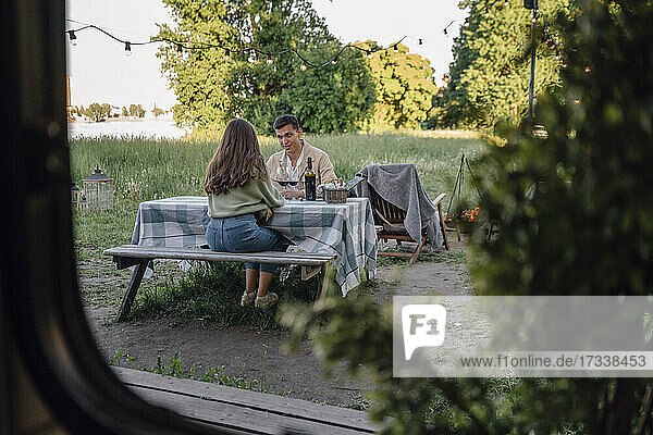 Junges Paar am Tisch sitzend durch das Wohnmobilfenster gesehen