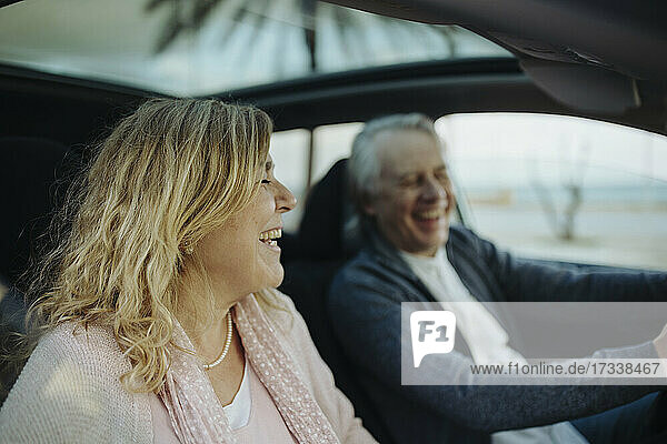 Reife blonde Frau lachend von Mann im Auto sitzend
