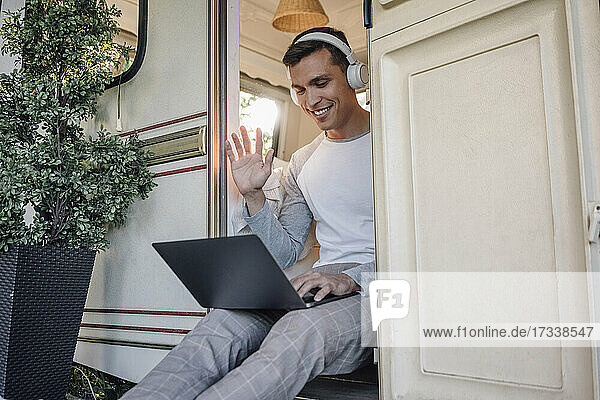 Smiling male freelancer waving hand during video call through laptop
