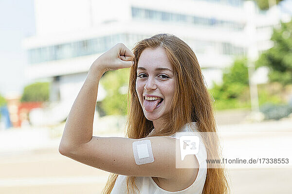 Geschäftsfrau mit Verband am Arm streckt während der Pandemie die Zunge heraus
