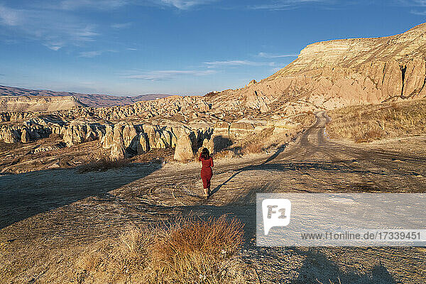Türkei  Kappadokien  Rückansicht einer Frau in rotem Kleid in felsiger Landschaft