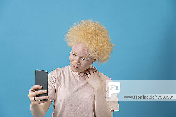 Studioaufnahme einer Albino-Frau mit Smartphone