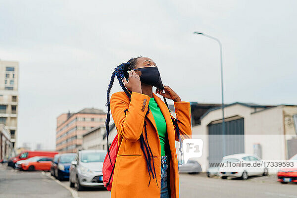 Italien  Mailand  Modische Frau nimmt Gesichtsmaske auf der Straße ab