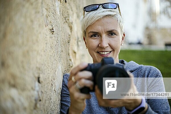 Porträt einer Frau mit der Digitalkamera in ihren Händen
