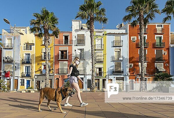 Junge Frau geht Hund vor bunten Häusern am Strand  Cases de Colors  Carrer Arsenal  Villajoyosa  Spanien  Europa