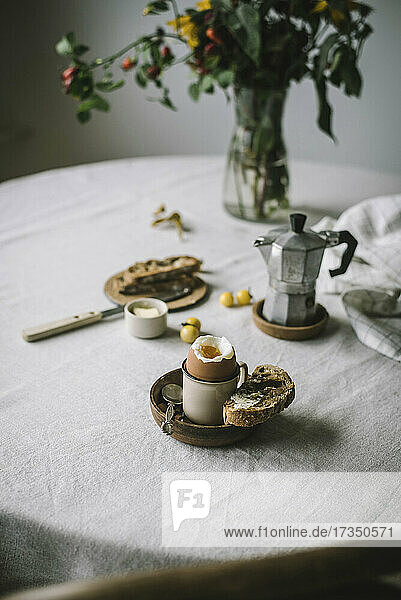 Gekochtes Ei  Brot und Espressokanne auf Frühstückstisch