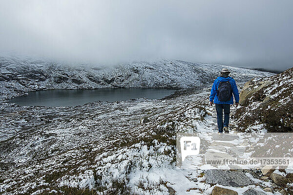 Australia  New South Wales  Woman hiking on snowy trail by lake at Charlotte Pass in Kosciuszko National Park