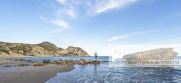 Young man standing on a rock  sandy beach with rocky cliffs  Paralia Paradisos  Kos  Dodecanese  Greece  Europe