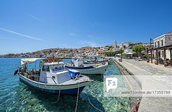 Fischerboote im Hafen von Chalki mit türkisblauem Wasser  Promenade mit bunten Häusern des Ortes Chalki  Chalki  Dodekanes  Griechenland  Europa