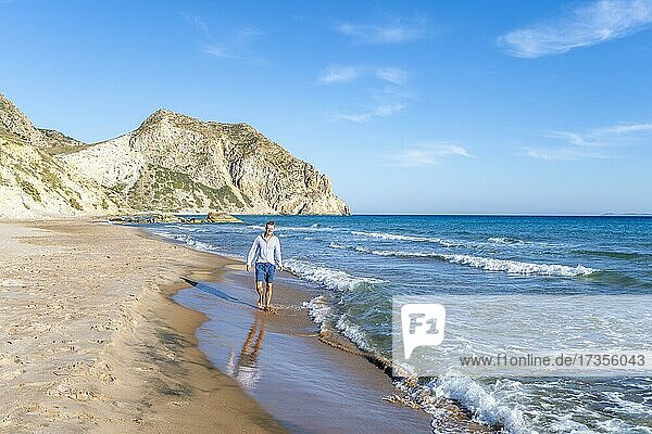 Young man walking on a beach  sandy beach with rocky cliffs  Paralia Paradisos  Kos  Dodecanese  Greece  Europe