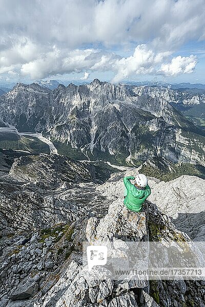 Hiker with helmet at the summit of the Watzmann  view over mountains  mountain range Hochkalterstock with Blaueisspitze and Hochkalter  hiking trail to the Watzmann  Watzmann crossing  Berchtesgaden  Bavaria  Germany  Europe