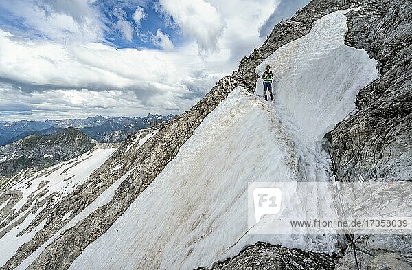 Wanderer beim Abstieg über Schneereste in felsigem Gelände  mit Stahlseil gesicherter Wanderweg  Heilbronner Weg  Allgäuer Alpen  Allgäu  Bayern  Deutschland  Europa