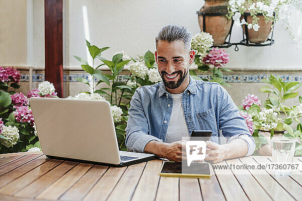 Smiling male professional talking during video call through laptop at backyard