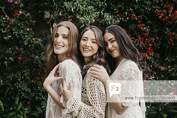 Lächelnde junge Frauen  die zusammen bei Pflanzen stehen
