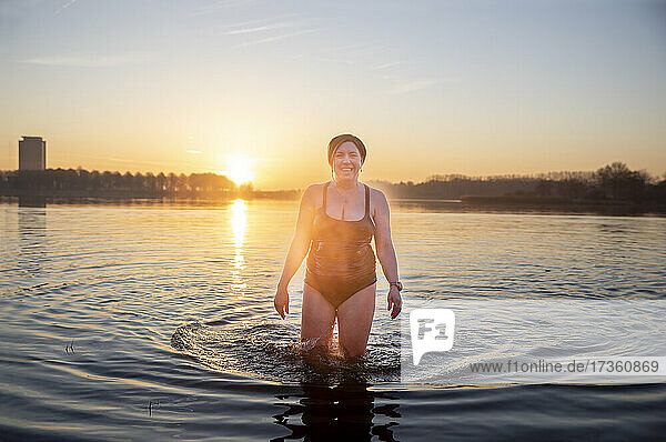 Lächelnde reife Frau im Wasser stehend am Morgen
