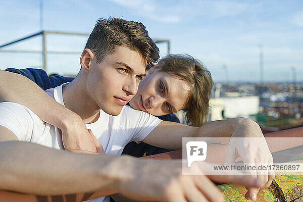 Young man looking at male friend on rooftop