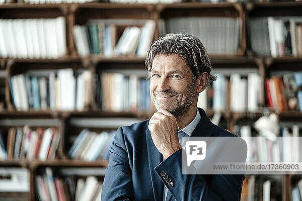 Smiling businessman with hand on chin in cafe