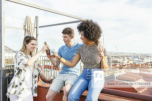 Junge männliche und weibliche Freunde stoßen mit Getränken auf einer Penthouse-Party an
