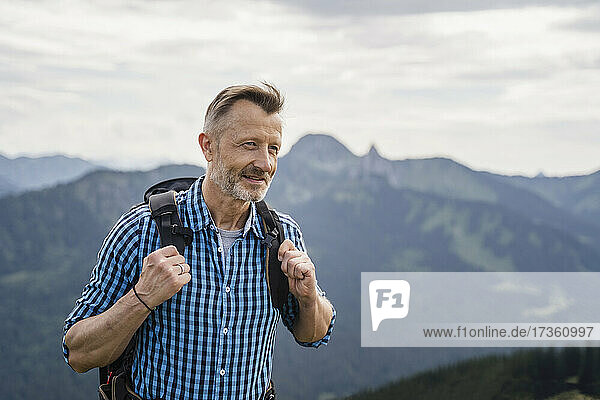Smiling male backpacker hiking on mountain