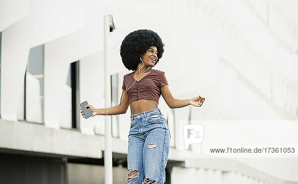 Glückliche Afro-Frau schaut beim Tanzen in der Stadt weg