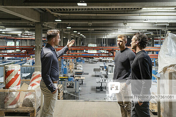 Businessman pointing while discussing strategy with colleagues at factory