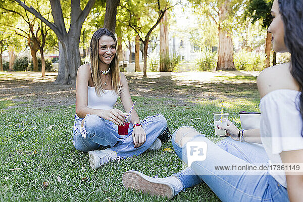 Weibliche Freunde  die zusammen im Park sitzen und etwas trinken