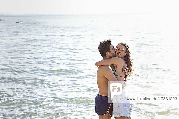 Boyfriend kissing while hugging girlfriend by Lake Trasimeno