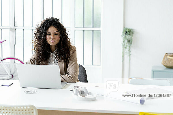 Young businesswoman working on laptop at desk in office