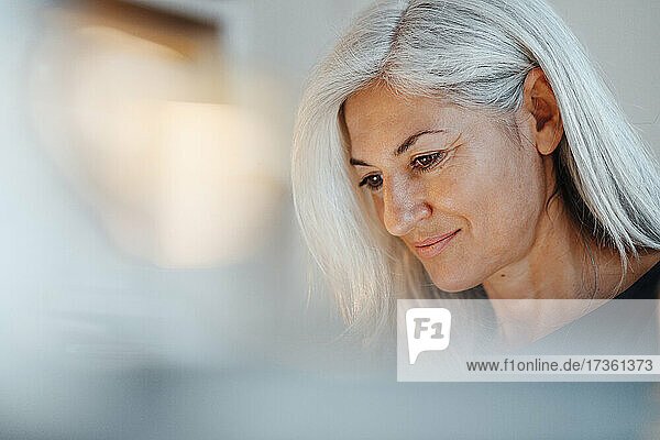 Reife Geschäftsfrau mit weißen Haaren  die auf ihr Büro hinunterblickt
