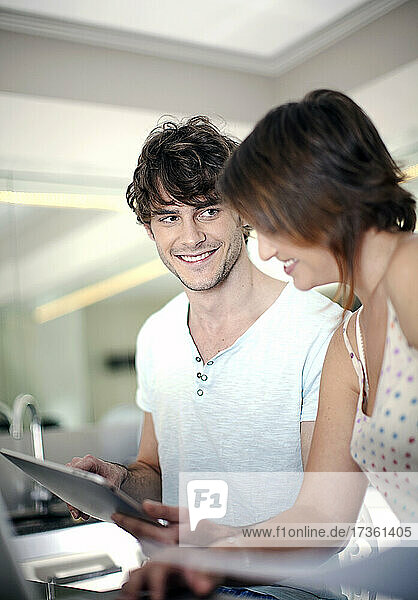 Smiling man sharing digital tablet with girlfriend at home