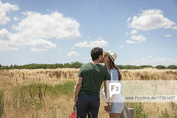 Couple kissing each other while standing on sunny day