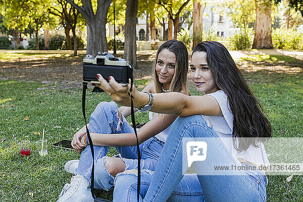 Frauen nehmen Selfie durch Kamera beim Sitzen im öffentlichen Park
