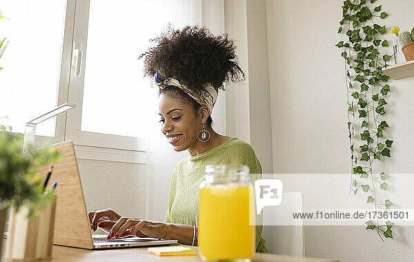 Smiling young businesswoman working on laptop in green house