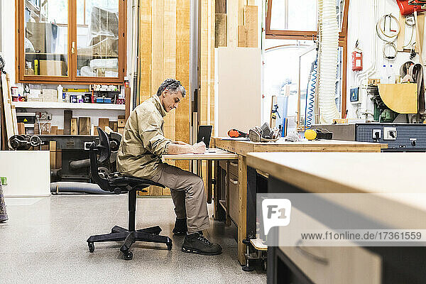 Male craftsperson working at table in workshop