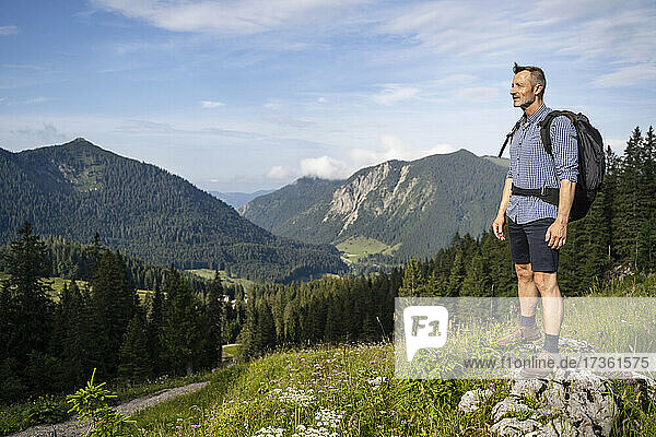 Male hiker with backpack looking at scenic landscape from mountain