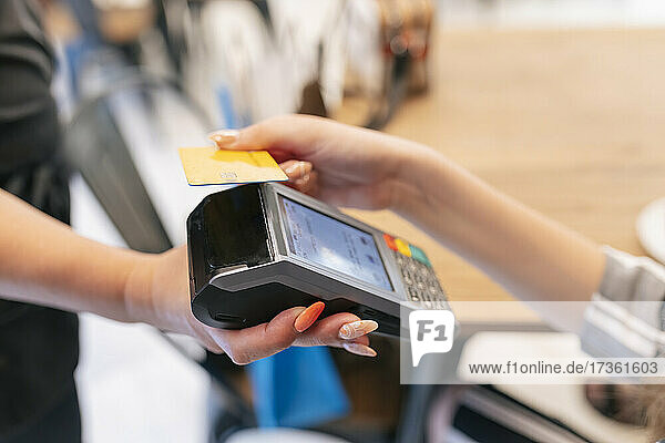 Frau zahlt mit Kreditkarte an Kellnerin im Food Court