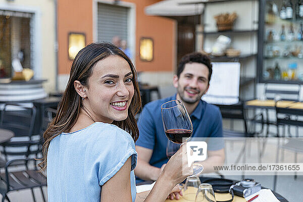 Glückliche Frau trinkt Wein mit ihrem Freund in einem Straßencafé