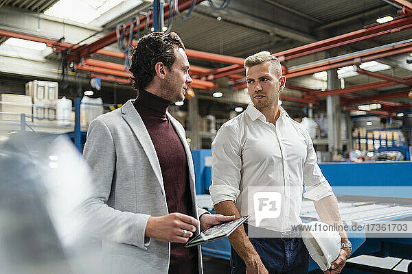 Businessman discussing with male engineer while walking at industry