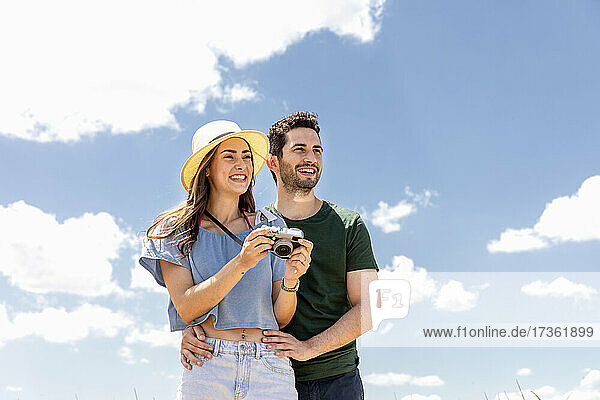 Happy couple with camera on sunny day