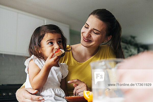 Daughter eating breakfast with mother at home