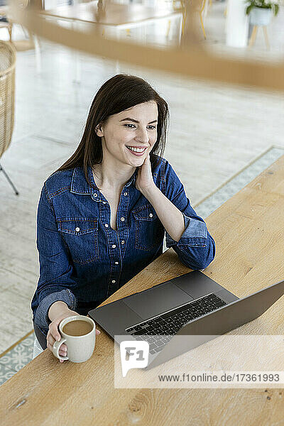 Nachdenkliche Geschäftsfrau mit Laptop  die am Tisch im Büro sitzt