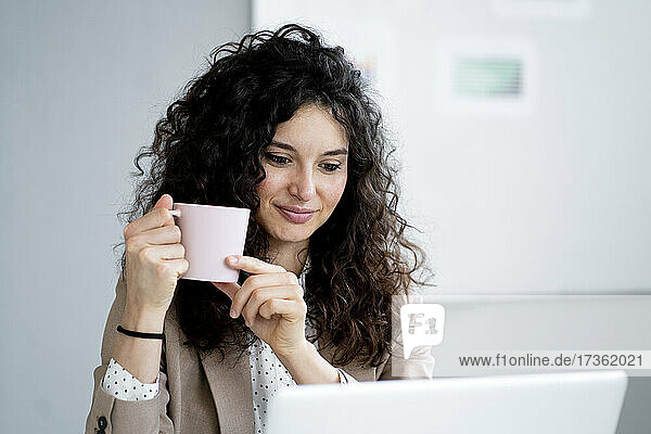 Geschäftsfrau mit Laptop und Kaffeetasse im Büro