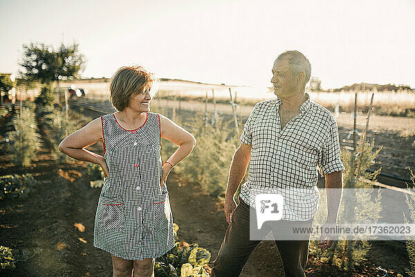 Smiling senior couple looking at each other while standing in field