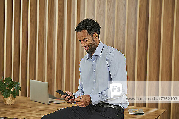 Businessman using mobile phone while sitting on conference table