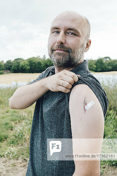 Geimpfter Mann zeigt Verband mit Tätowierung am Arm