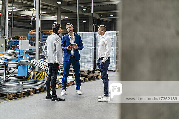 Male professionals having discussion while standing in factory