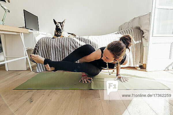 Frau übt Yoga auf einer Übungsmatte im Schlafzimmer einer Wohnung