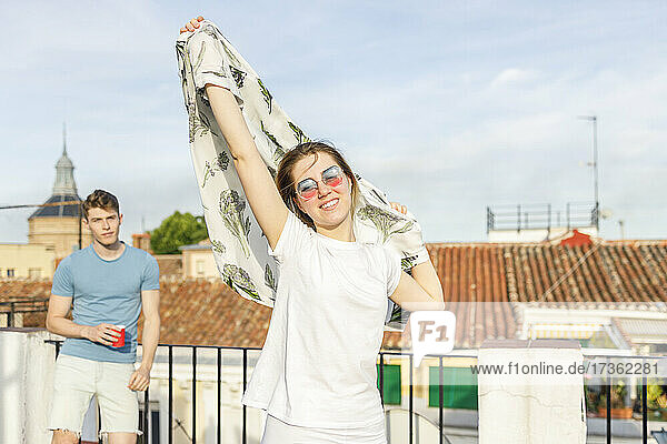 Junge Frau tanzt mit Kopftuch auf einem Dach