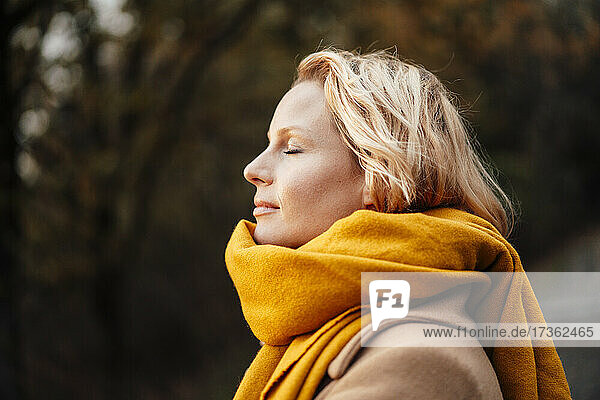 Blond woman with eyes closed wearing shawl