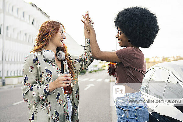 Smiling female friends giving high-five on road